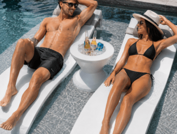 Signature Chaise pool loungers with Ari table and headrest pillows in a luxury swimming pool