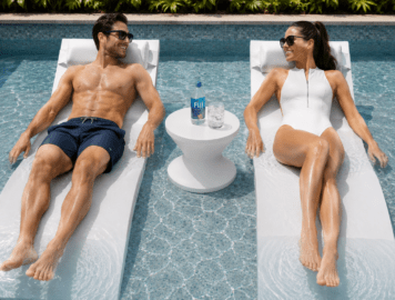 Two Signature Chaise pool loungers with Ari in-pool table and headrest pillows on a luxury tanning ledge.